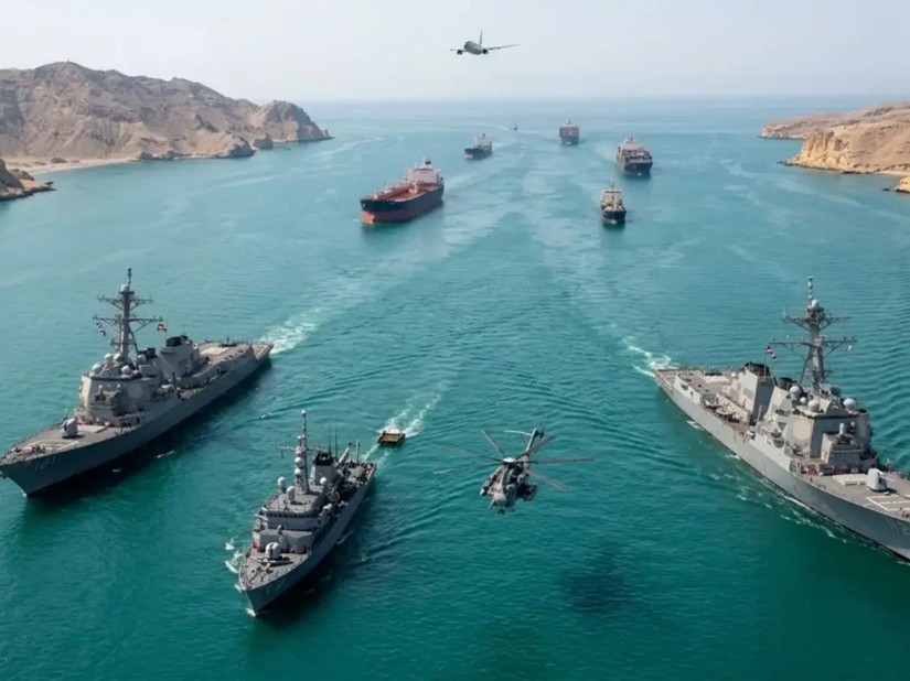 Naval warships and aircraft patrolling the Strait of Hormuz alongside commercial cargo ships